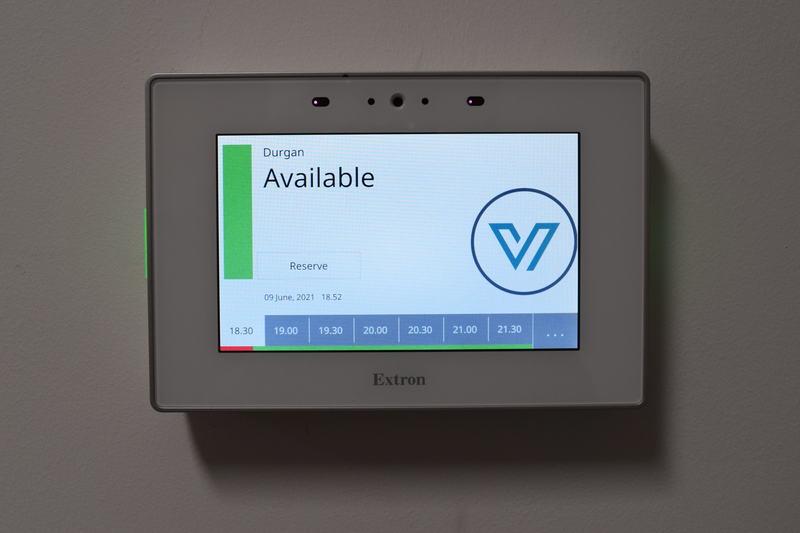 Wall-mounted Extron digital touchscreen showing a conference room’s availability
